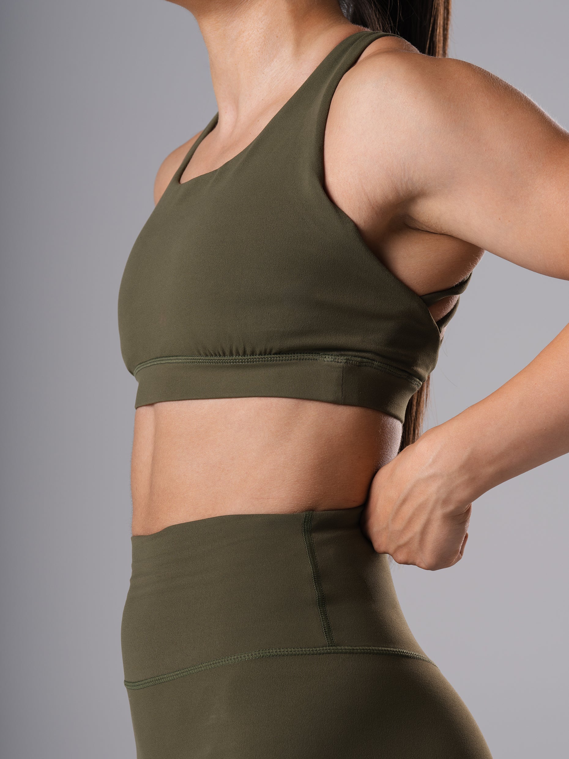 Seitliche Nahaufnahme des Power Form Sports Bra in Olive Night von Atletica mit passenden Shorts