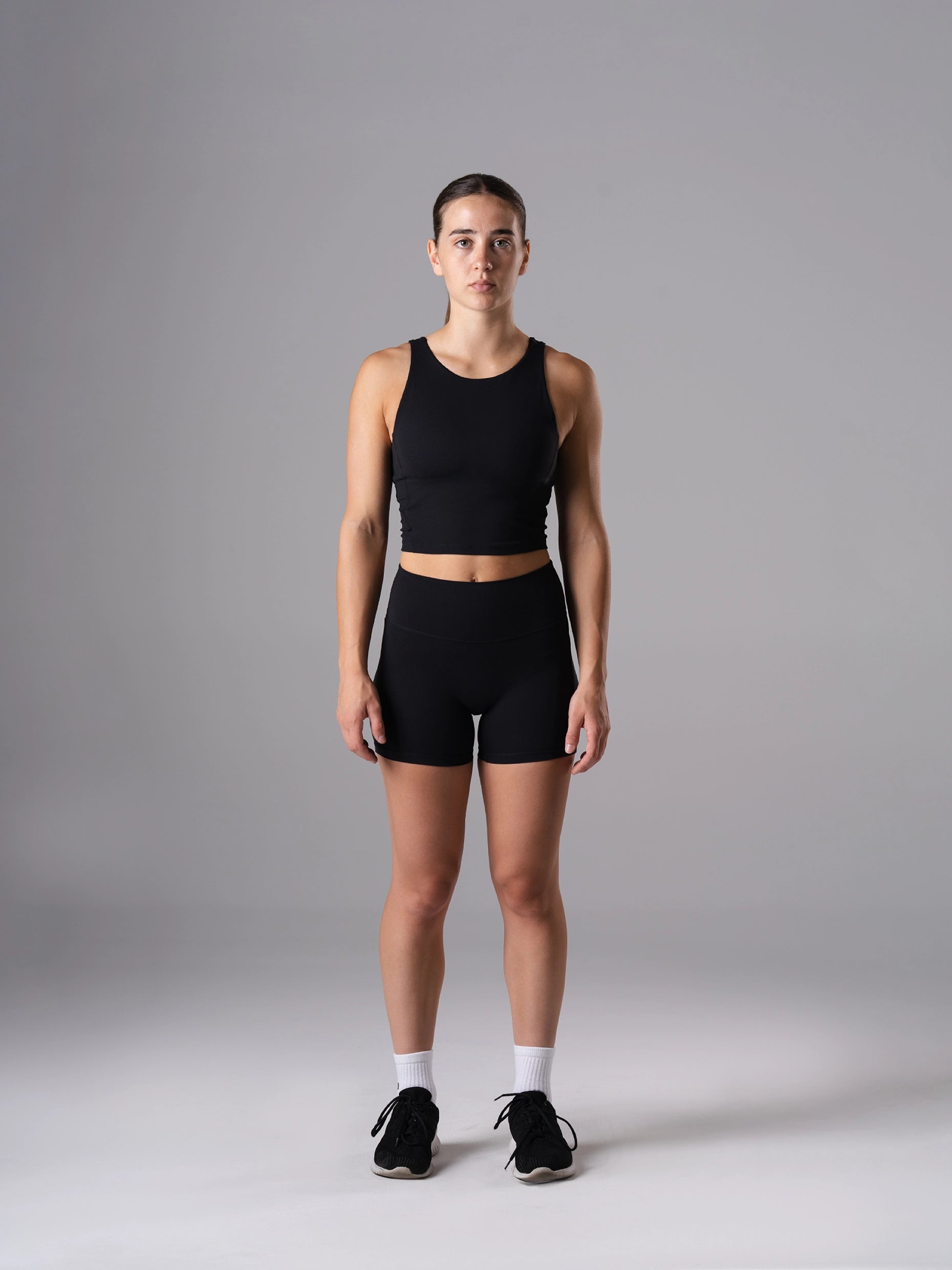 Ganzkörperansicht: Frau im Power Form Tank Top Bra in Schwarz von Atletica mit passenden Shorts