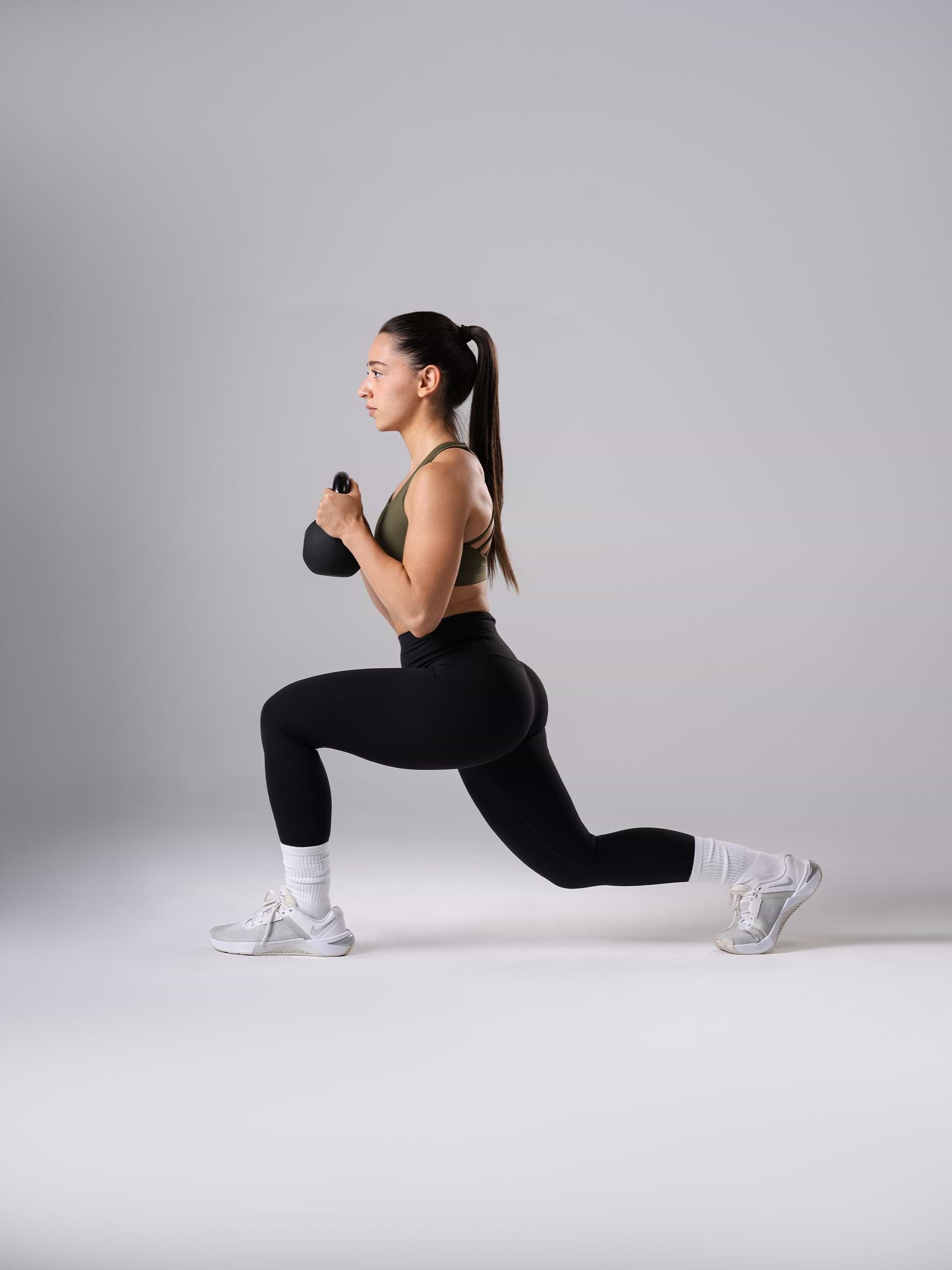 Frau in den schwarzen Power Form Tights von Atletica beim Ausfallschritt mit Kettlebell