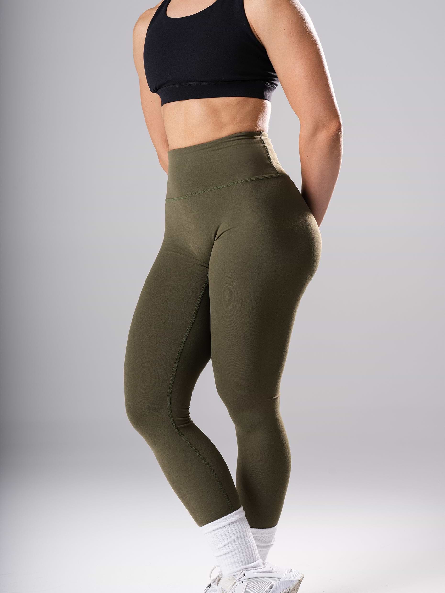 Frau in den Power Form Tights in Olive Night von Atletica mit schwarzem Sport-BH, Seitenansicht