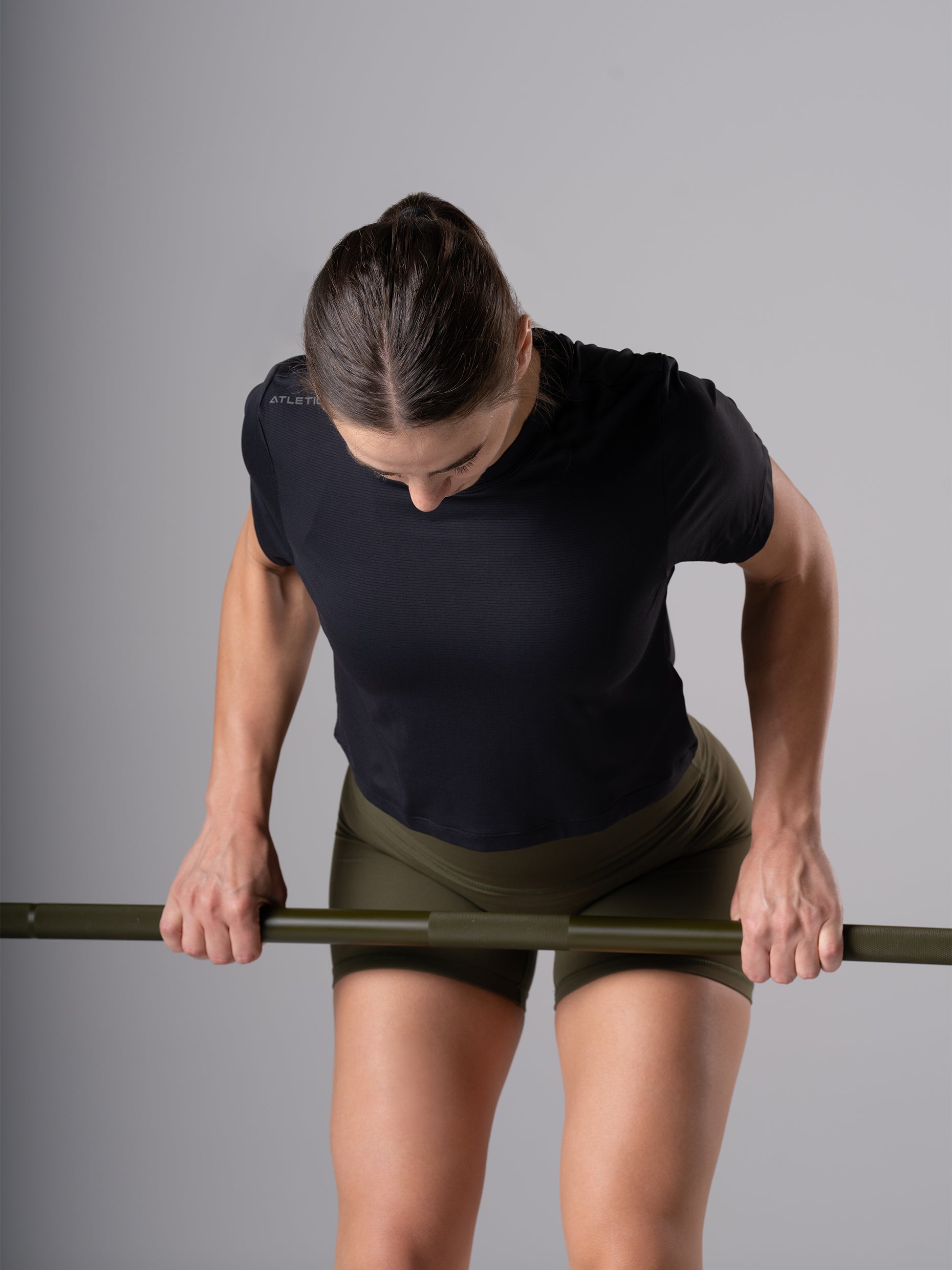 Frau im schwarzen Power Lift Cropped T-Shirt von Atletica beim Kreuzheben mit Langhantel