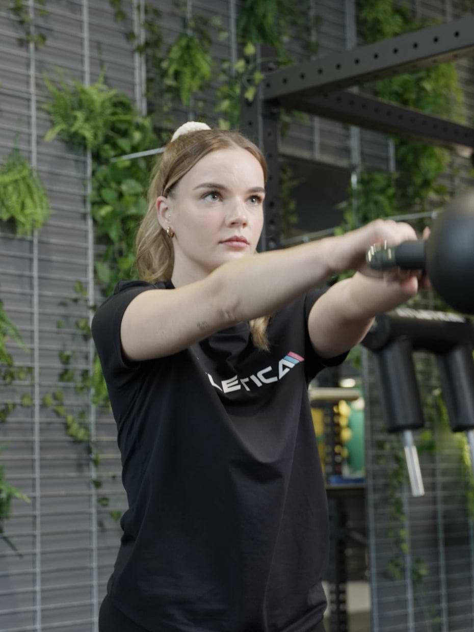 Atletica Kettlebell 12 kg beim Einsatz im Fitnessstudio - Frau führt Kettlebell Swings aus