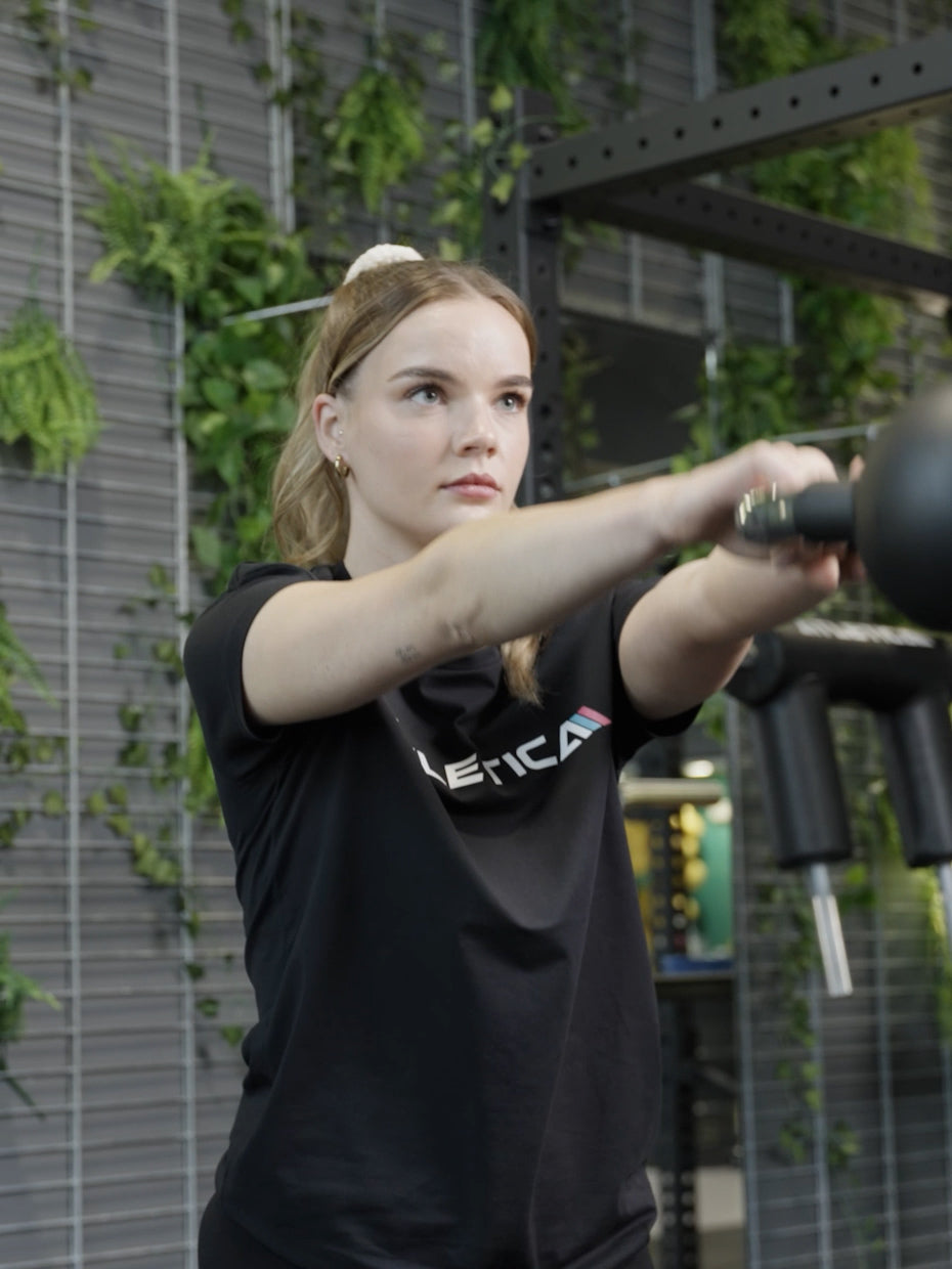 Atletica Kettlebell 12 kg beim Einsatz im Fitnessstudio - Frau führt Kettlebell Swings aus