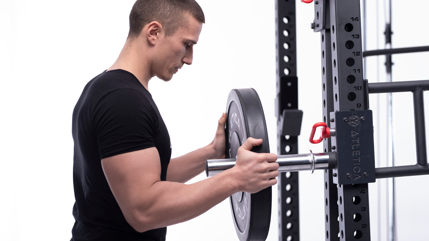 Man placing weight plates on the weight plate holders of the R8 Power Rack