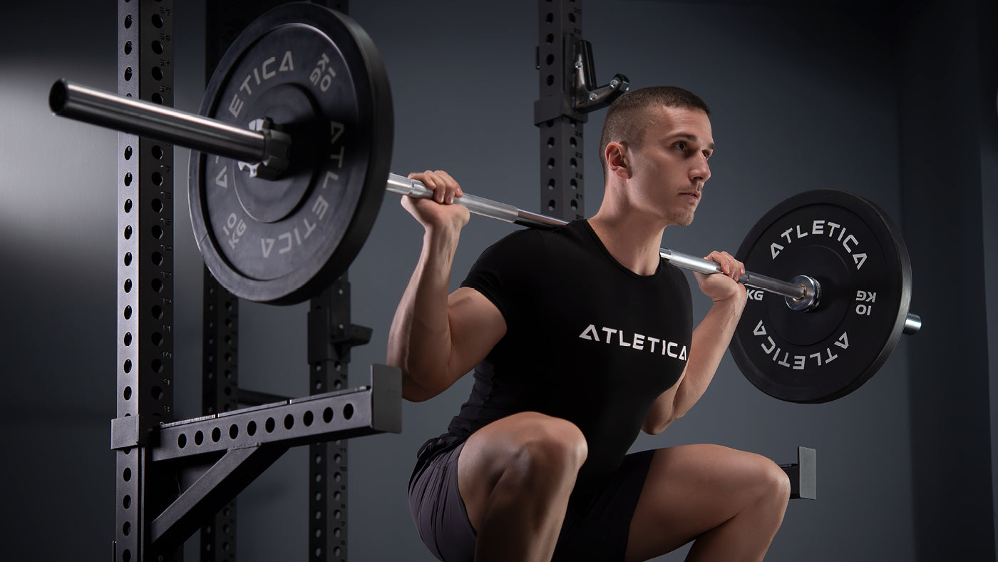Dřep s osou a bumper kotouči na squat racku s bezpečnostními rameny