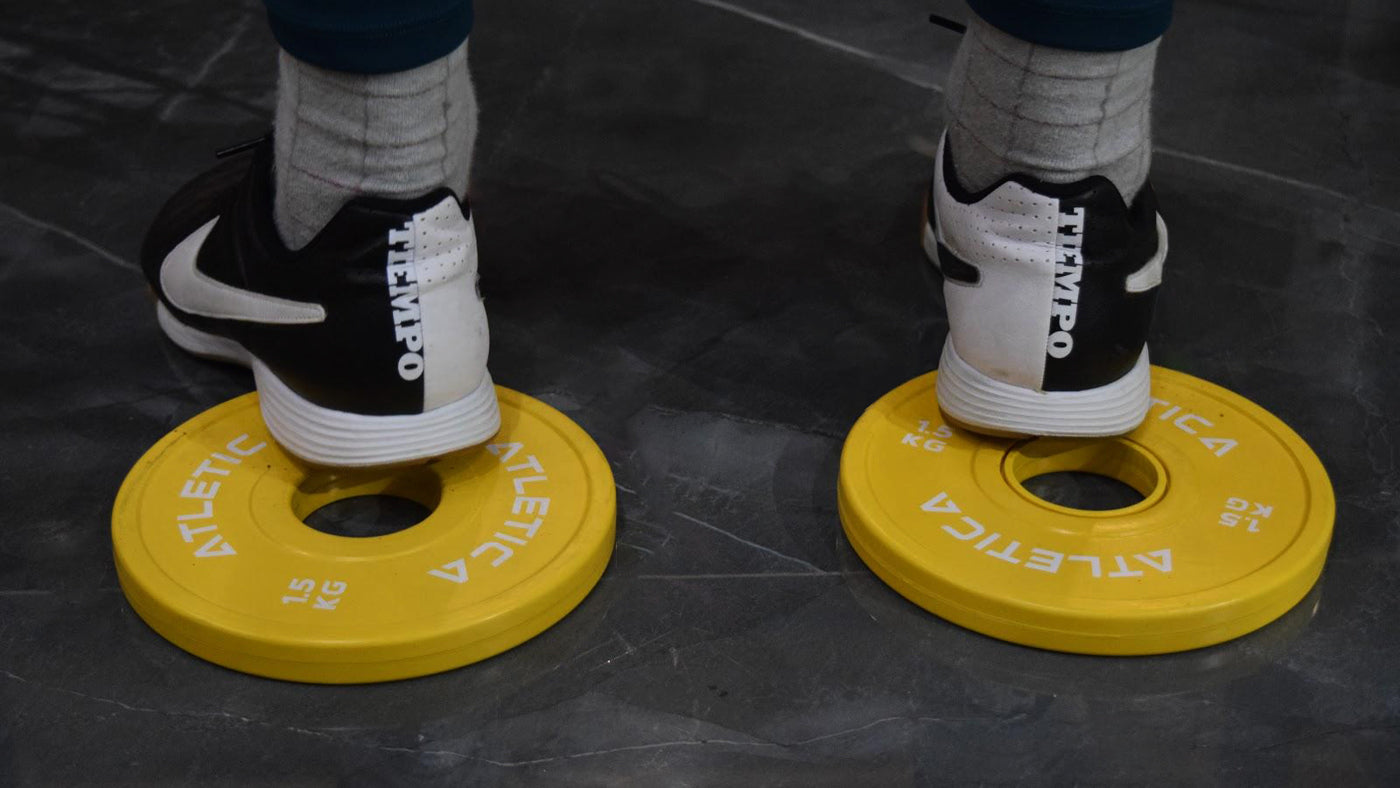 Athlet steht mit den Fersen auf den Atletica Fractional Add-On Plates in gelb 