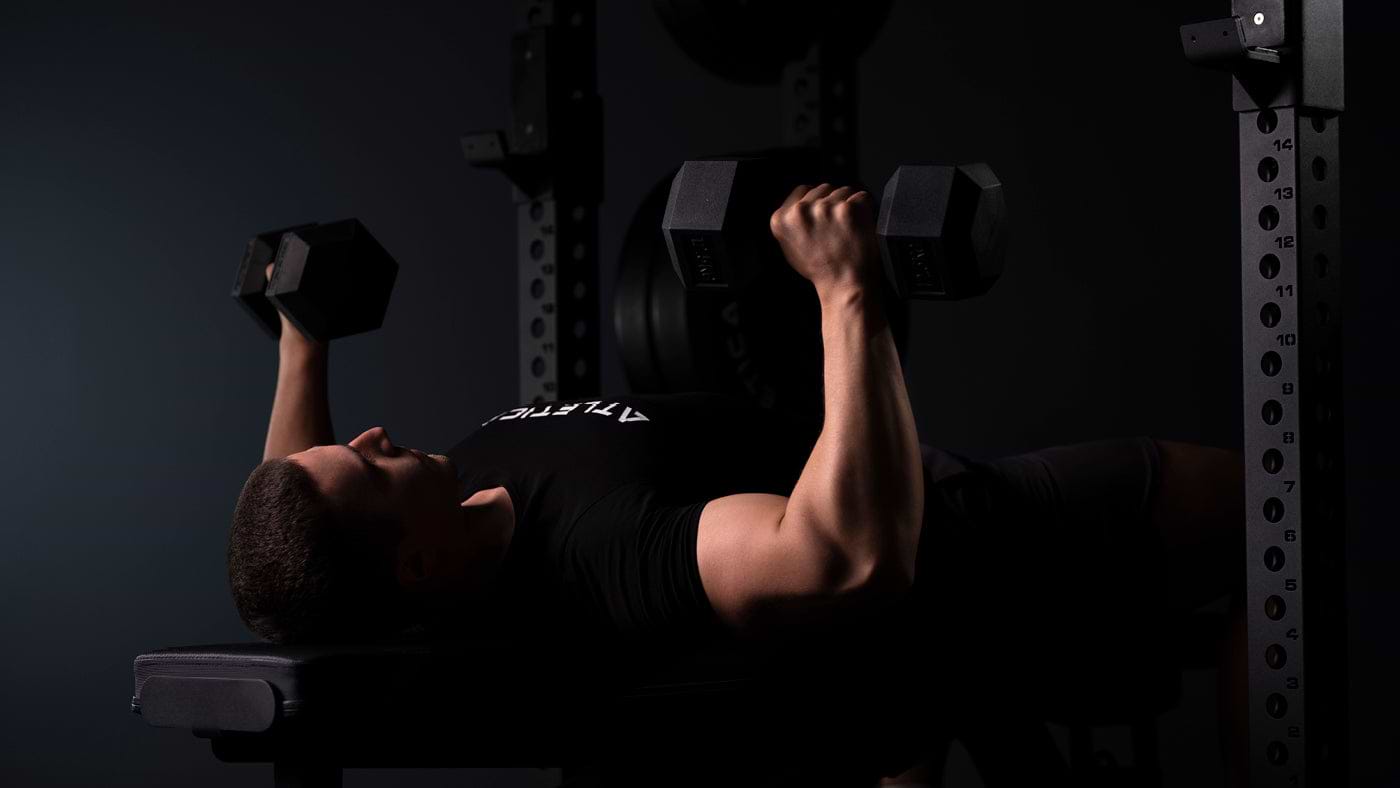Athlet führt Kurzhantel-Bankdrücken mit zwei Hexagon Kurzhanteln im Gym aus