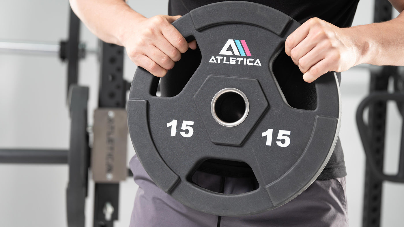 Athlet hält Atletica Gripper Plate Hantelscheibe 15 kg