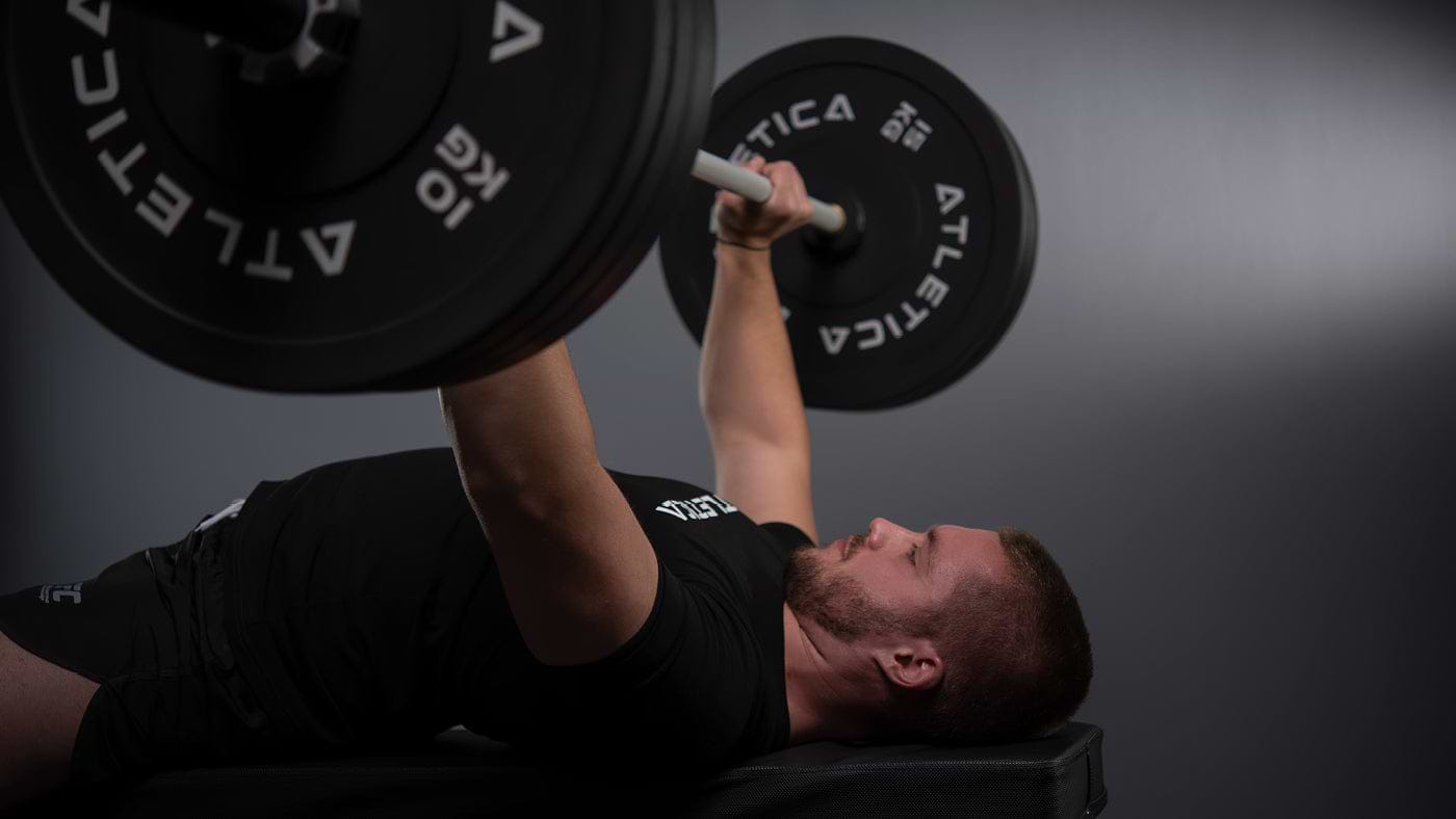 Bankdrücken mit Atletica Langhantel und schwarzen Bumper Plates