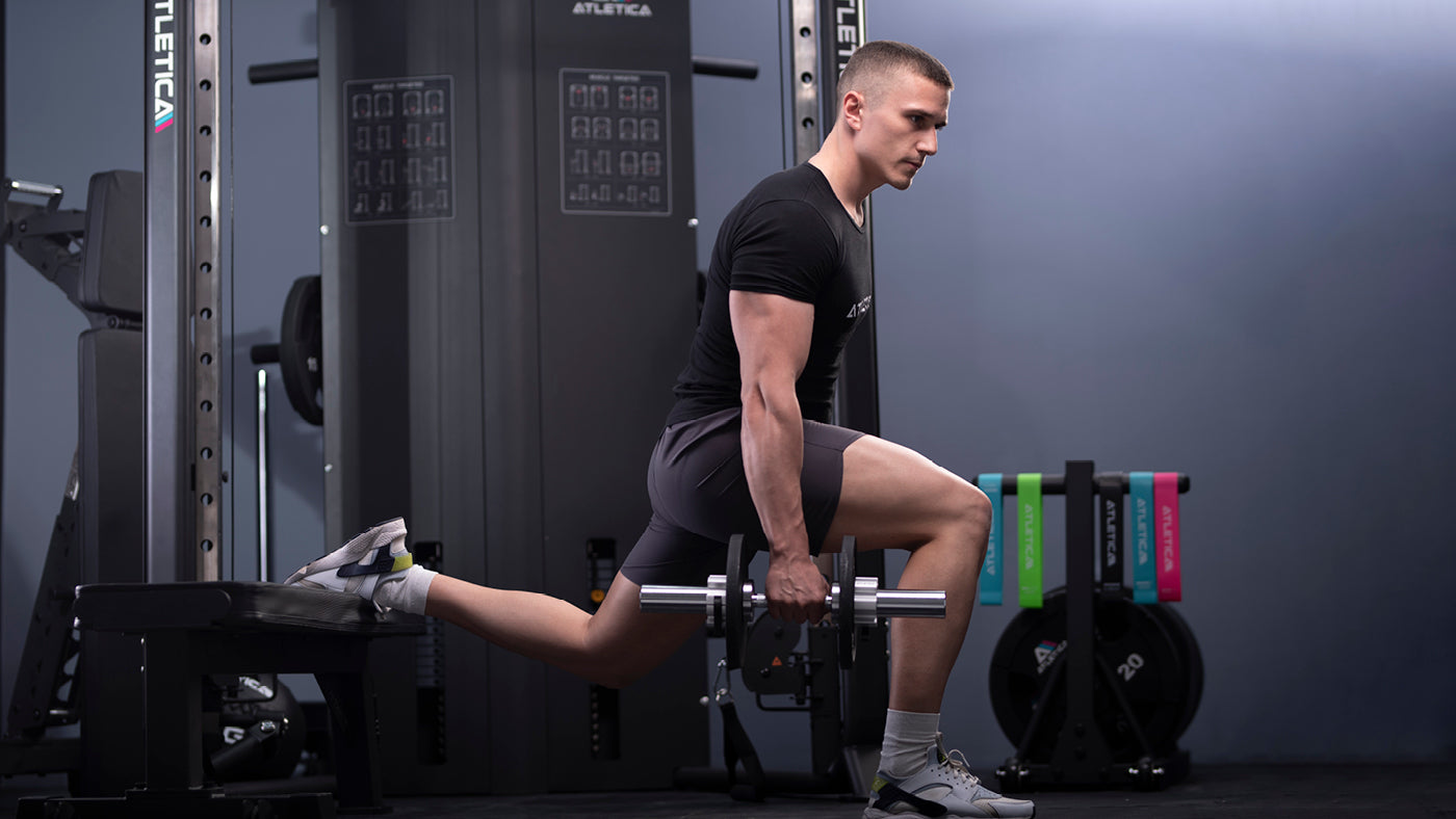 Lunges s krátkou tyčí na tréninkové lavici ve fitness centru