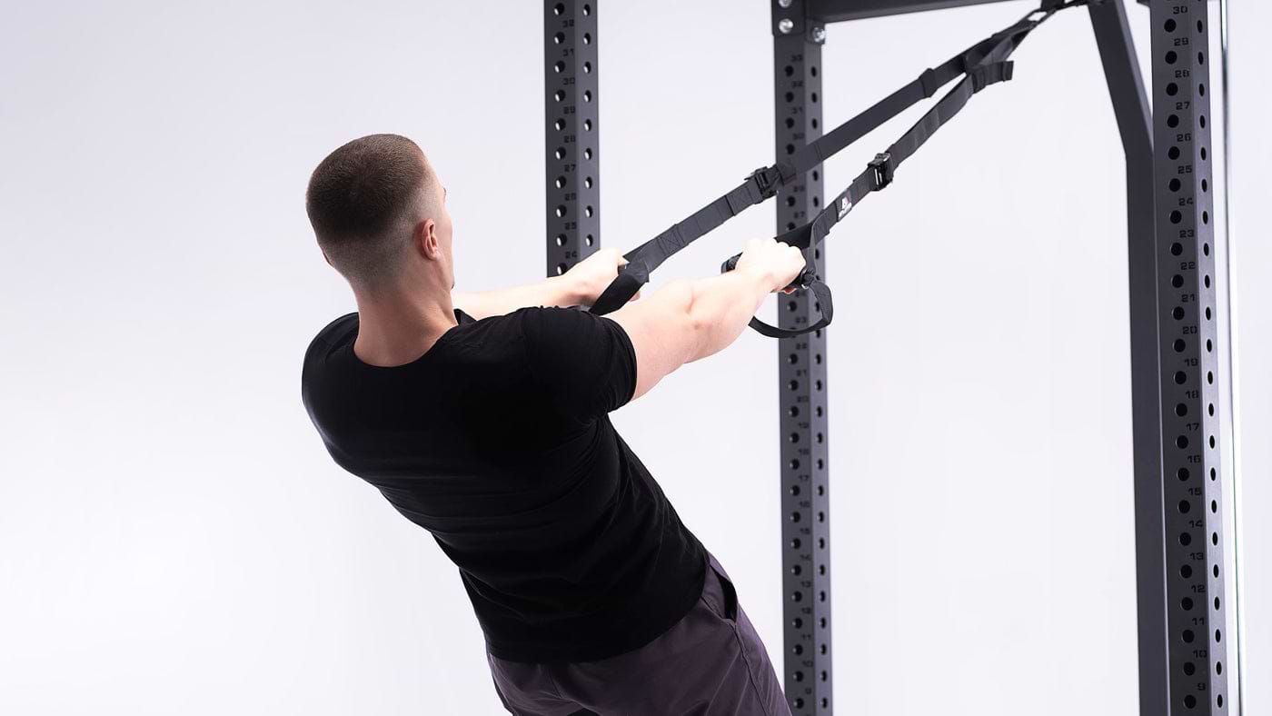 Vue de dos d'un homme en entraînement en suspension avec des poignées en D