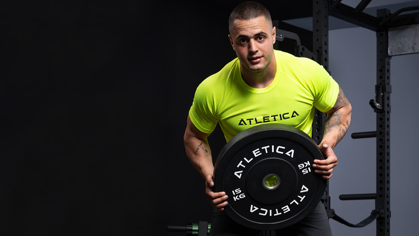 Karlos Nasar houdt een zwarte Atletica bumperschijf van 15 kg vast