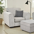 Thornby Standard Armchair Light Grey Charcoal from Roseland Furniture in a living room whith white walls and light oak floors, on the left is a tree in a woven plant pot and on the right a lamp and a footstool