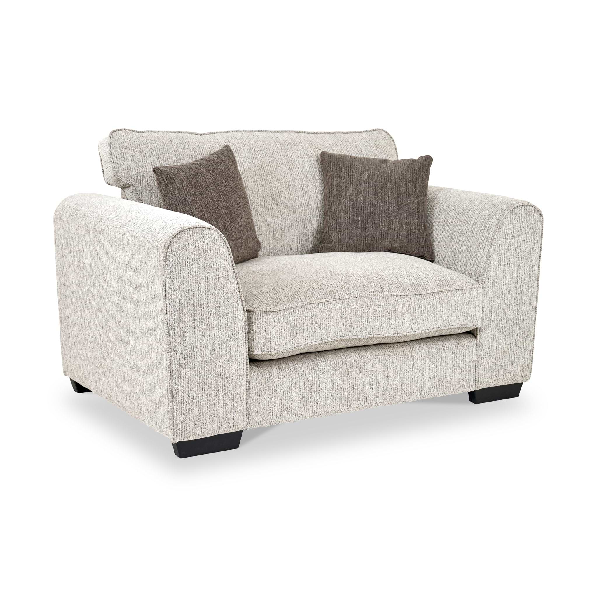 Thornby Snuggle Armchair Natural Mink from Roseland Furniture postitioned at an angle highlighting the black legs and textured details of the armchair with simple piping around the edges and 2 brown cushions