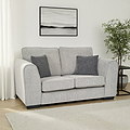 Thornby 2 Seater Sofa Light Grey Charcoal from Roseland Furniture in a living room adjacent to a window in a lounge with white walls and light oak flooring with a cream colour rug. to the right is a back side table and a tree and above is an abstract painting.