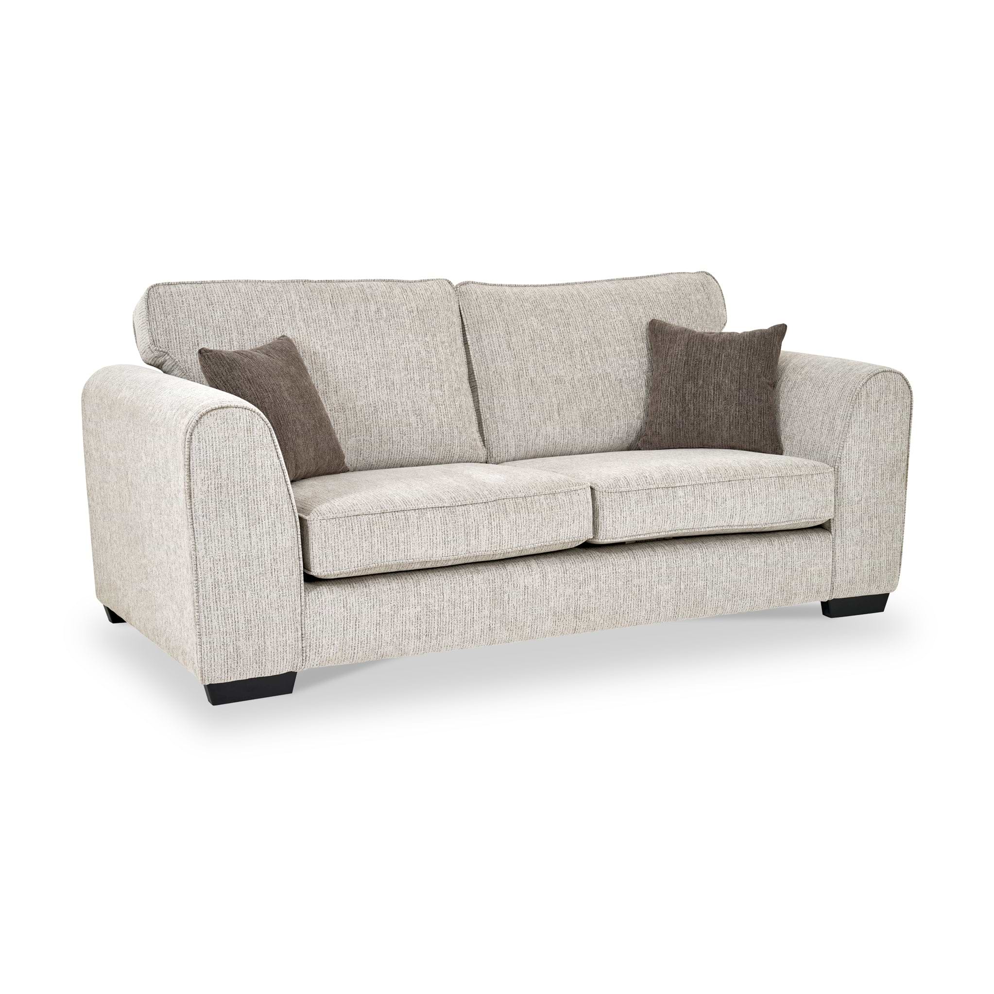 Thornby 3 Seater Sofa Natural Mink from Roseland Furniture postitioned at an angle highlighting the black legs and textured details of the sofa with simple piping around the edges and two Brown cushions.