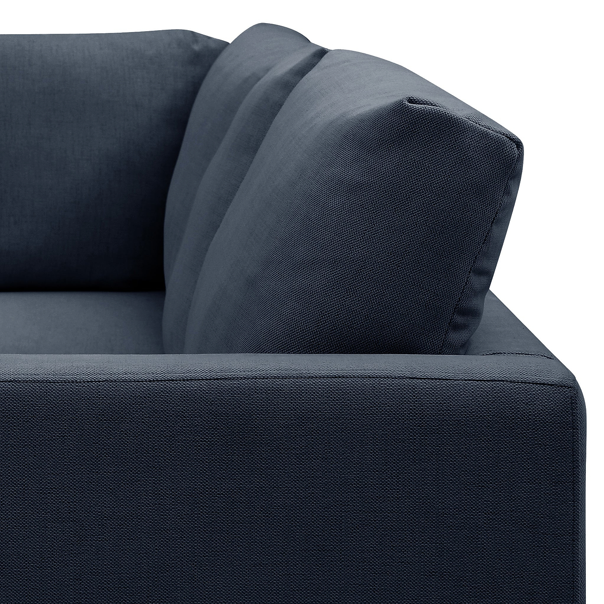 A close-up of a section of a dark blue sofa showing textured fabric, a cushion, and armrest against a white background.