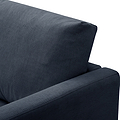 A navy blue fabric sofa against a stark white background, focusing on the armrest and backrest.