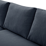 A grey fabric sofa with a cylindrical cushion resting on its surface, set against a neutral background.