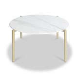 A round table with a white marble top and gold-colored legs stands stationary against a plain white background.