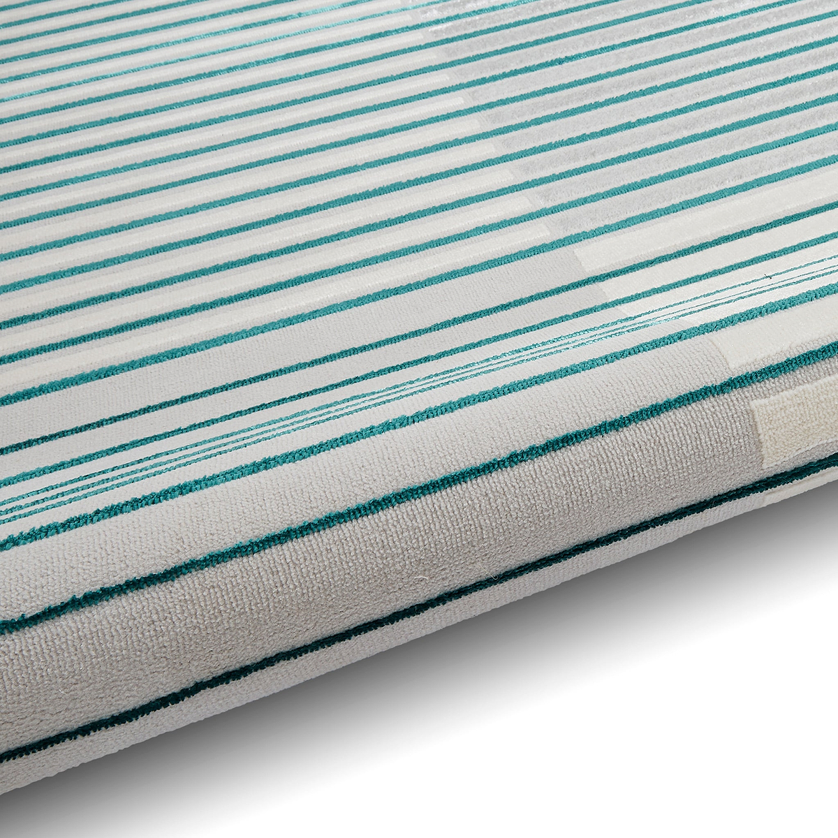A striped mattress with a white background and parallel teal lines is partially visible, angled and resting on a white surface.