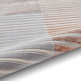 A striped rug with varying shades of gray, white, and rose lies flat, showcasing its texture and color gradient.