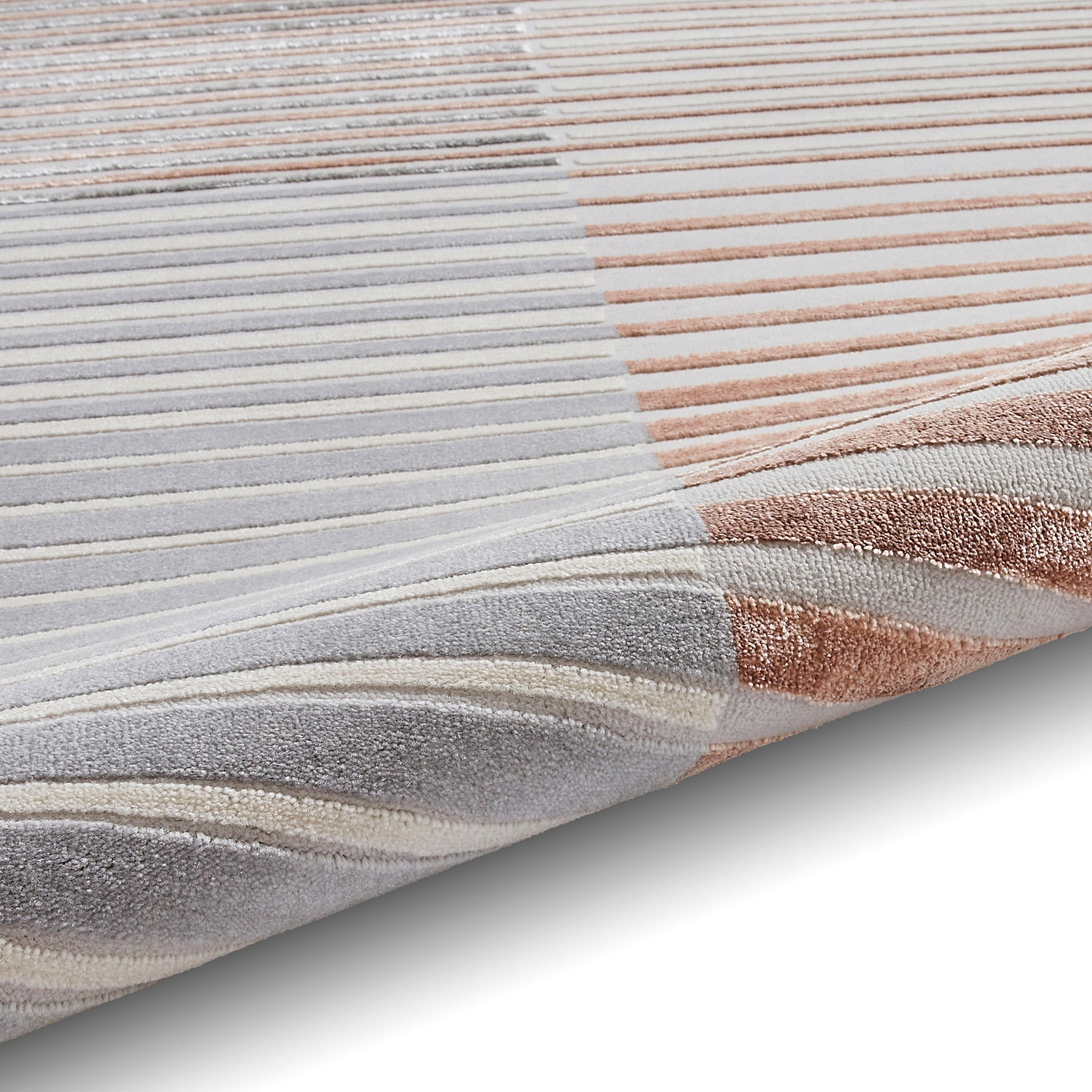 A striped rug with varying shades of gray, white, and rose lies flat, showcasing its texture and color gradient.