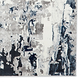 A textured rug with abstract gray, white, and navy brushstroke patterns creates a modern art-inspired appearance, seemingly displayed against a white backdrop.