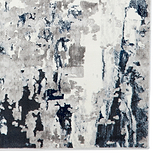 A textured rug with abstract gray, white, and navy brushstroke patterns creates a modern art-inspired appearance, seemingly displayed against a white backdrop.