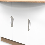Two reflective cabinet knobs on a white door panel, positioned symmetrically, with a wooden countertop overhead.