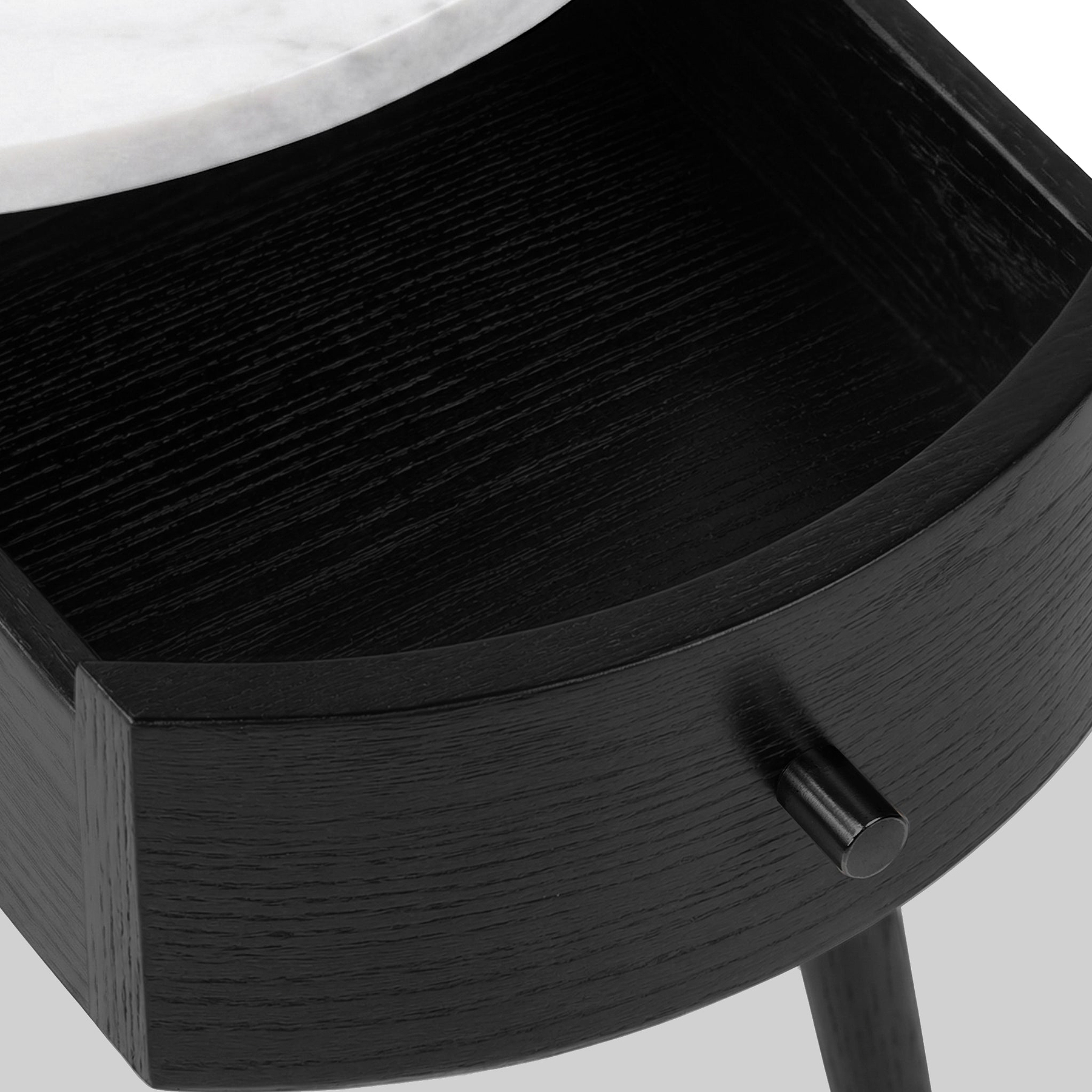 Close-up of a Shorwell Black & Marble 1 Drawer Side Table drawer with a curved front, a small round black knob, and part of a white marble tabletop visible at the top edge.