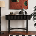 A modern Shorwell Black & Marble Oval Console Table  with a black slatted frame, white marble top, and black legs, styled in a living room setting with books, a candle, and decorative rocks.