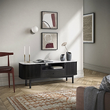 Modern Shorwell Black & Marble Slatted 130cm TV Unit from Roseland Furniture with a white marble top, styled in a minimalist living room with herringbone wood floors, a patterned rug, and abstract wall art.