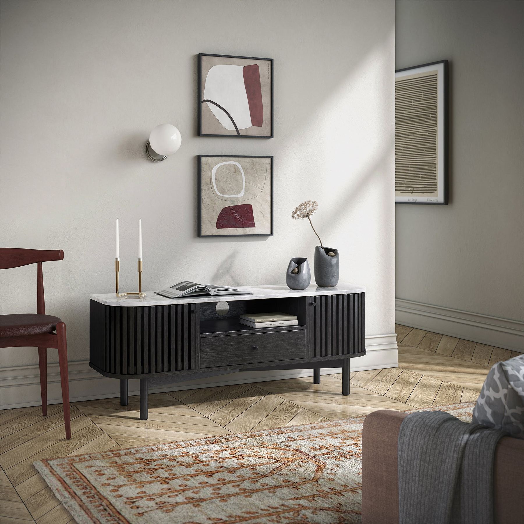 Modern Shorwell Black & Marble Slatted 130cm TV Unit from Roseland Furniture with a white marble top, styled in a minimalist living room with herringbone wood floors, a patterned rug, and abstract wall art.