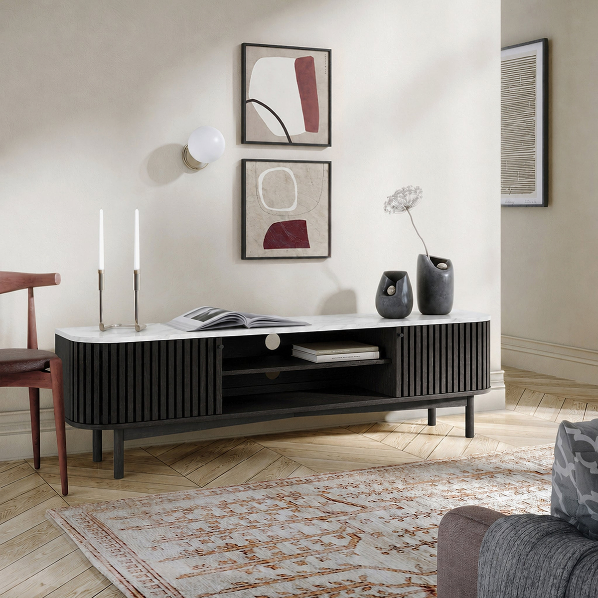 A modern Shorwell Black & Marble Slatted 180cm TV Unit in a styled living room setting, featuring a white marble-look top, a black ribbed cabinet body, and open shelving.