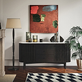 A modern Shorwell Black & Marble 3 Drawer Sideboard with a white marble top, styled in a living room setting with a black floor lamp, a potted palm, and an abstract painting on the wall.