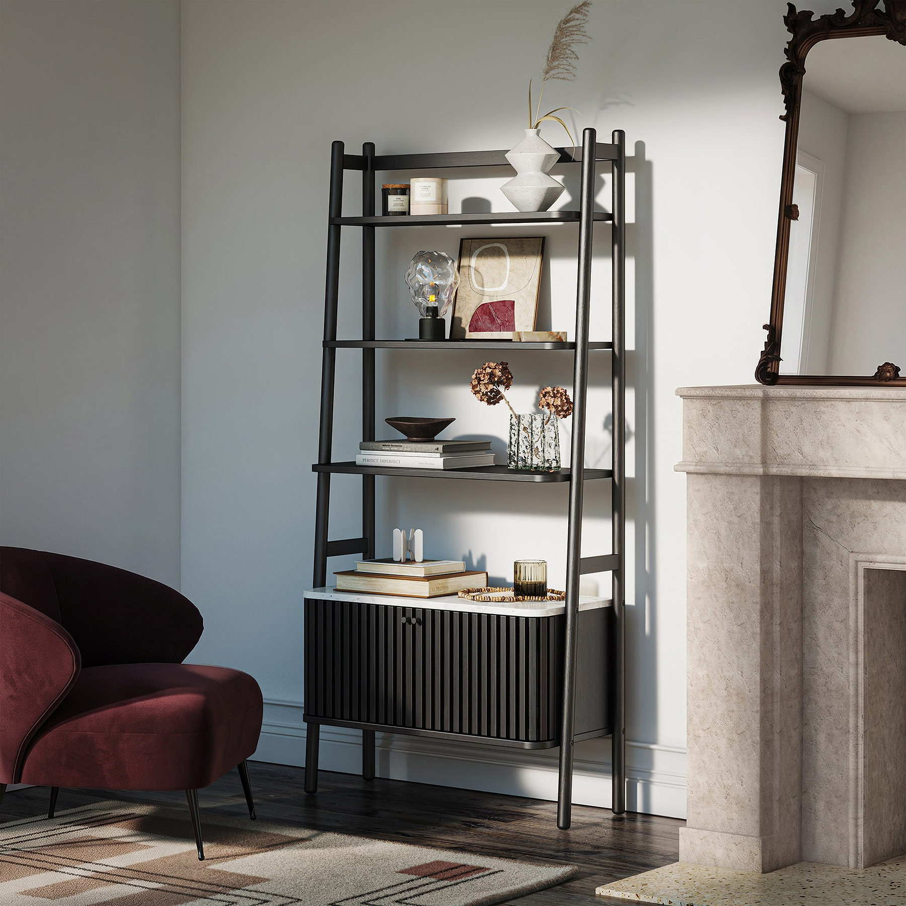 A Shorwell Black & Marble Bookcase with a slatted lower cabinet door, styled with books, vases, and decor in a modern living room next to a burgundy armchair and a stone fireplace.