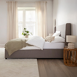 Brent Ottoman Storage Bed Frame from Roseland Furniture- Modern bedroom with a bed, side table, and lamp.