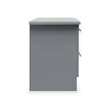 A grey, freestanding pedestal with a flat top, gold handles, and a drawer slightly ajar, isolated against a white background.