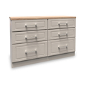 A wooden six-drawer dresser with a light brown top and silver handles sits idle in a white void.