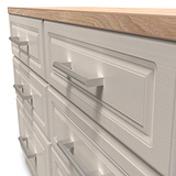 A wooden countertop rests on a gray cabinet with several closed drawers, featuring metallic handles, against a blank background.