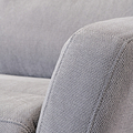 Close-up of a grey fabric sofa showcasing texture, with focus on the armrest and cushion in a home interior setting. No text present.