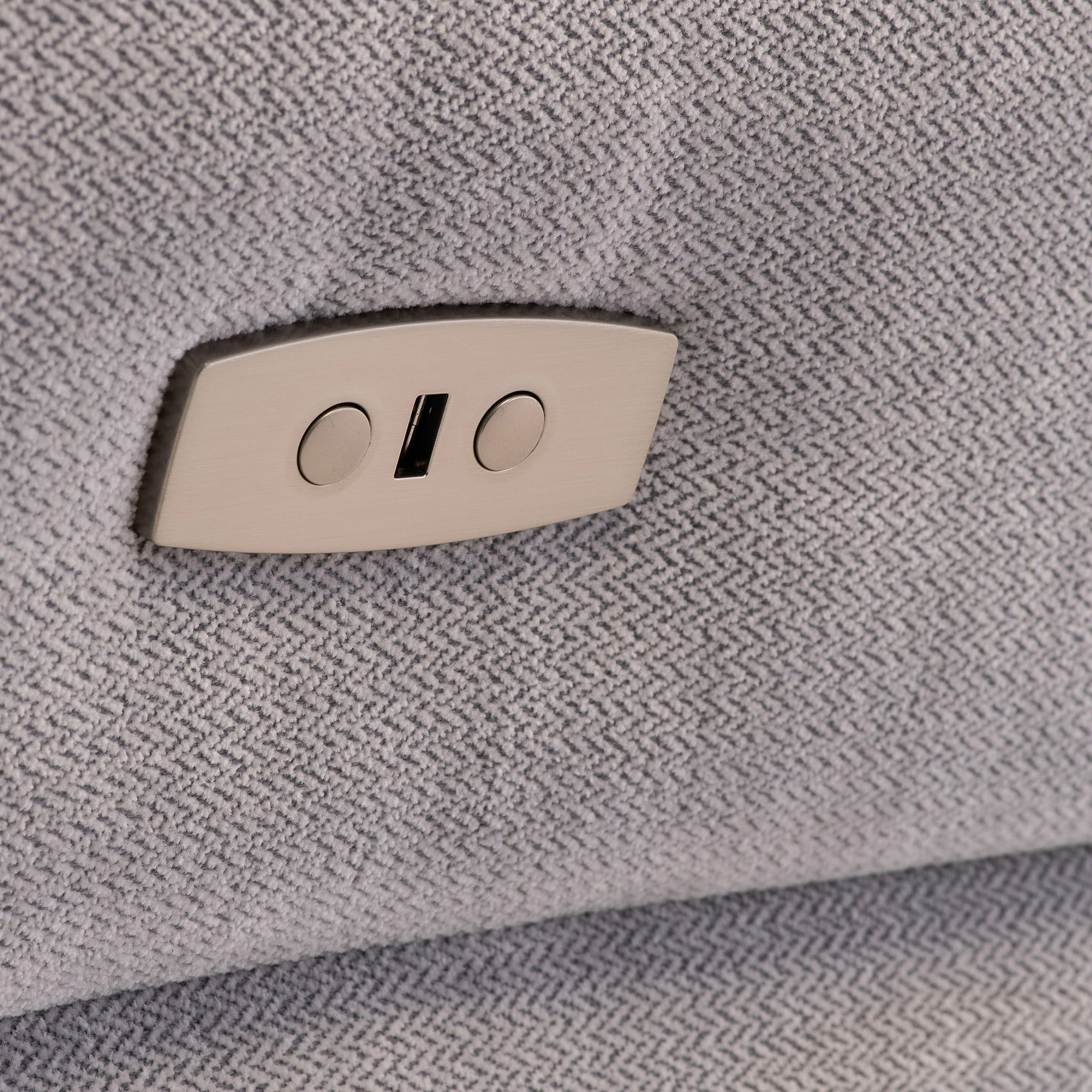 A dual USB port is mounted on a textured grey fabric surface, typically found in contemporary furniture or public transport seating.