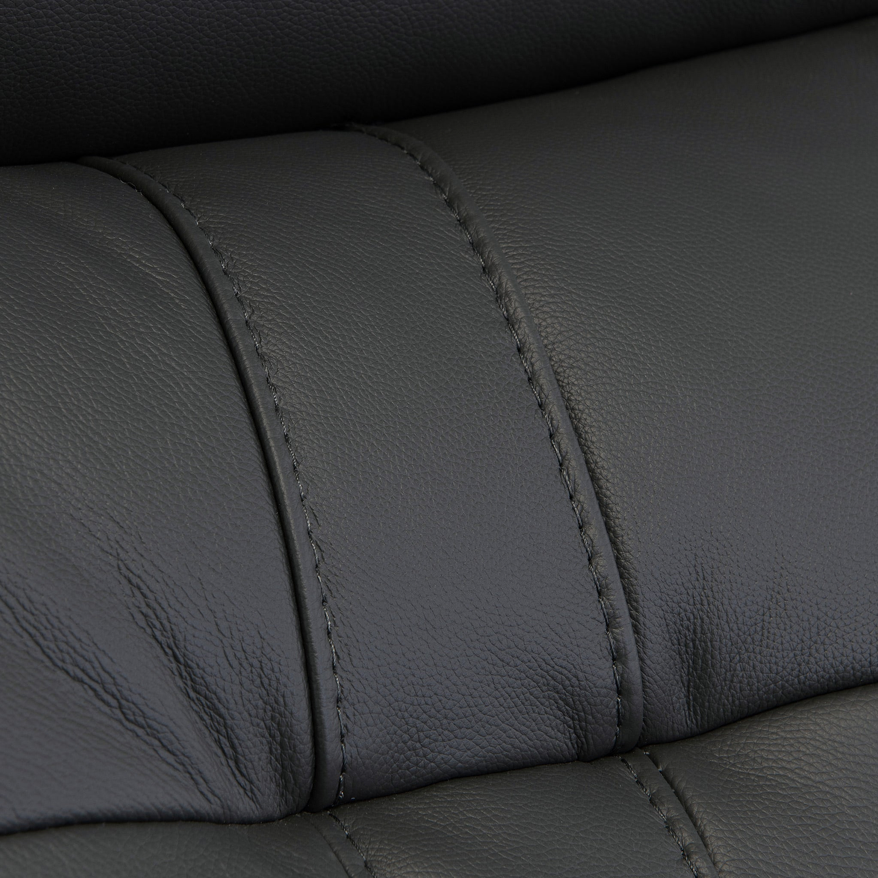 Black leather texture with visible stitching detail, creating a pattern of upholstered segments; likely from furniture such as a couch or car seat.