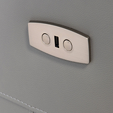 A metallic coat hook with two circular indents is mounted on a textured gray surface, providing a place to hang items.
