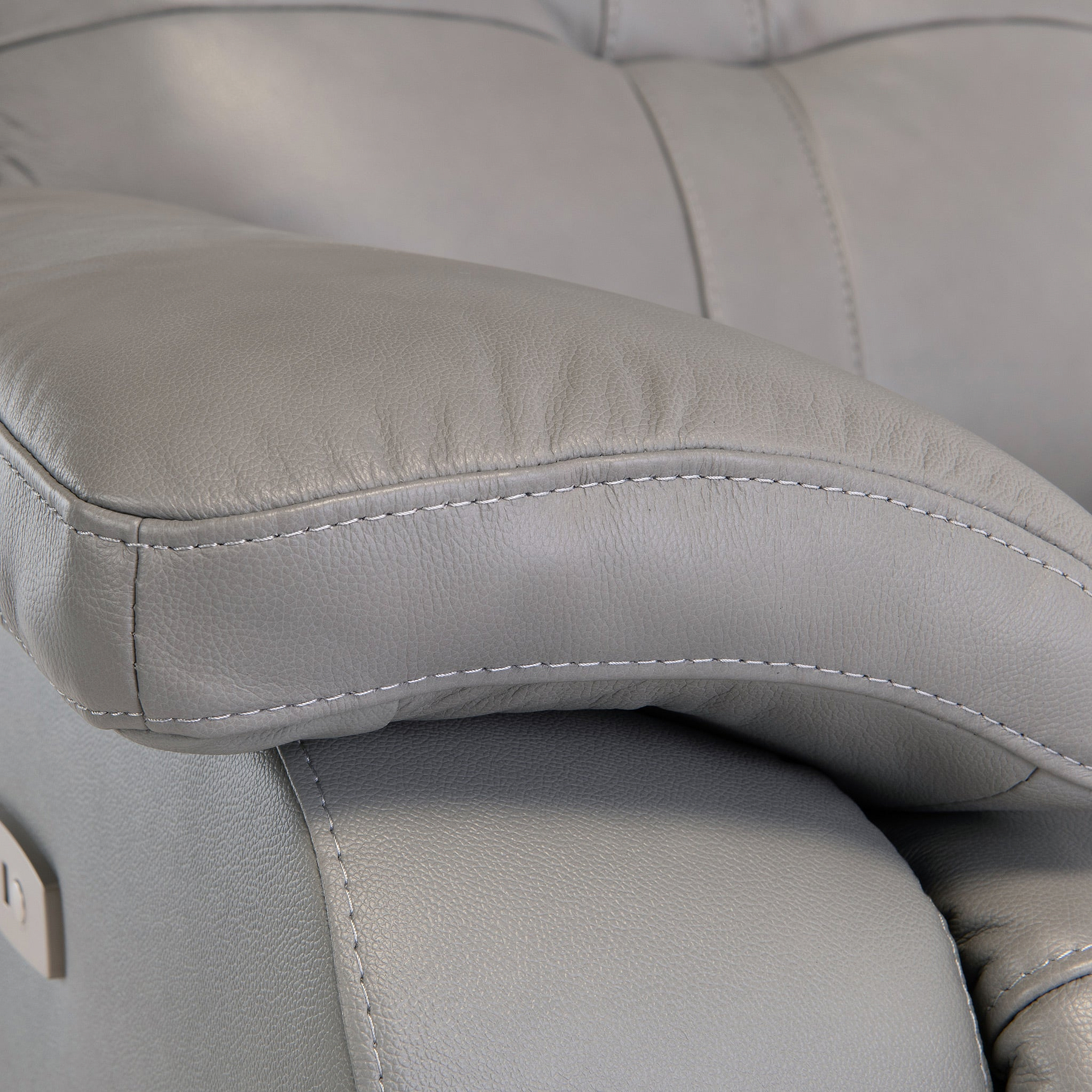 A close-up of a gray leather armchair with prominent stitching, highlighting texture and comfort.