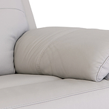 A cylindrical leather pillow rests against the arm of a cream-colored sofa, providing comfort and support within a minimalistic setting.