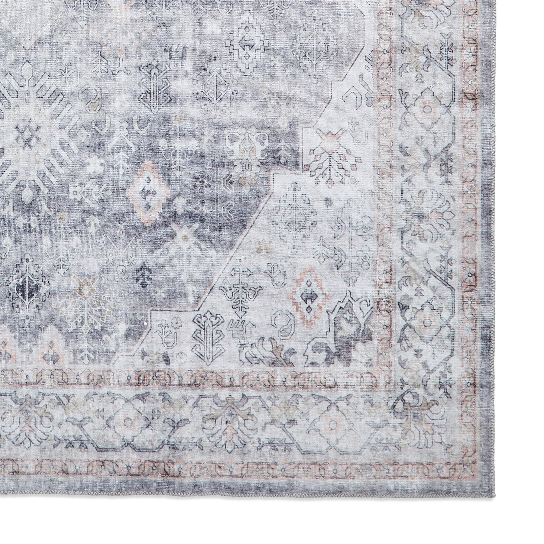 A vintage-style rug with intricate patterns and faded colors, predominantly in shades of gray and beige, rests against a white backdrop.