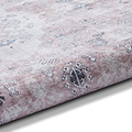 A patterned rug with a gradient from white to pink lies flat, showcasing traditional designs. The texture appears soft and plush.