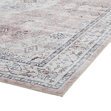 A detailed, vintage-style rug with a distressed pink and gray pattern lies flat on a white background.